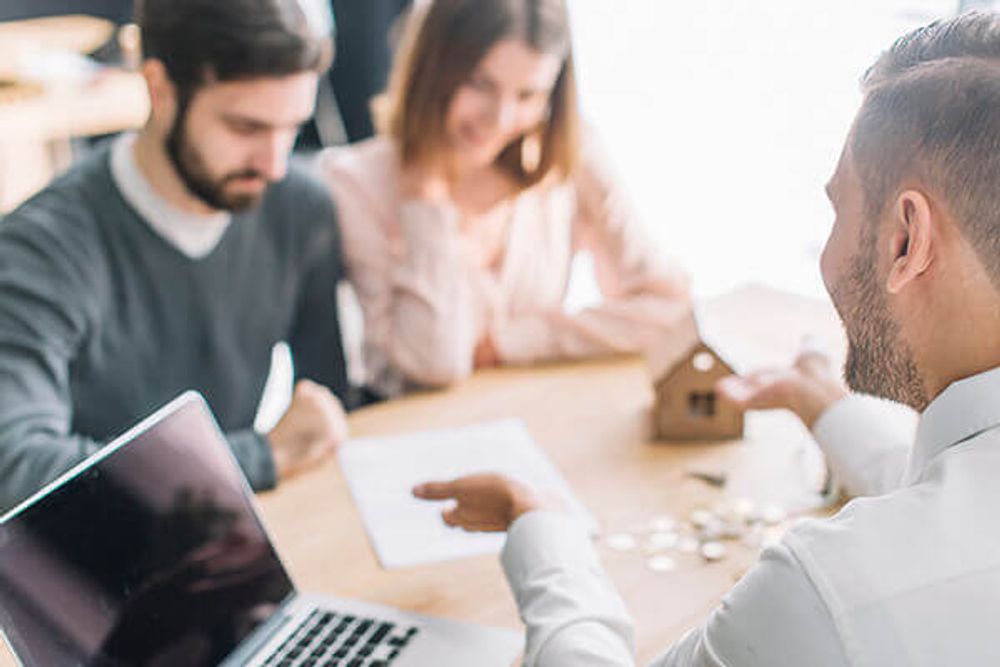 a group of people sitting around a table looking at a laptop
